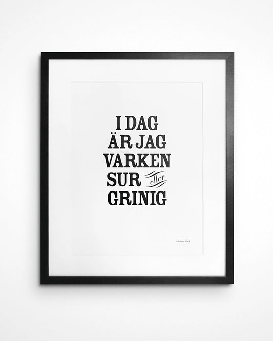 Poster med svenska citatet "Idag är jag varken sur eller grinig" i ram på vägg.