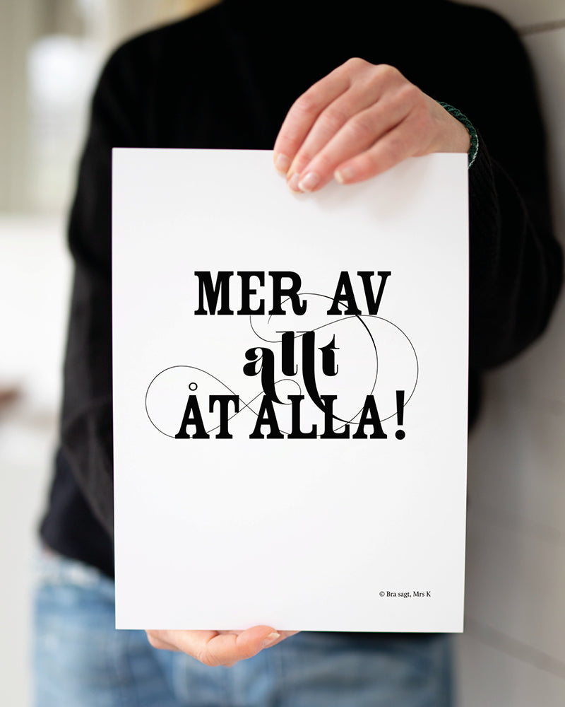 Mrs K håller upp poster med svenska citatet "Mer av allt åt alla".