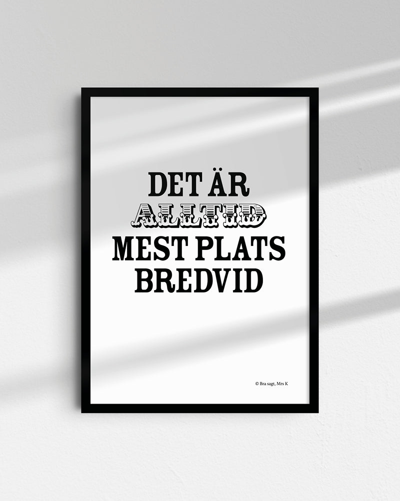 Poster med svenska citatet "Det är alltid mest plats bredvid" i ram på vägg.