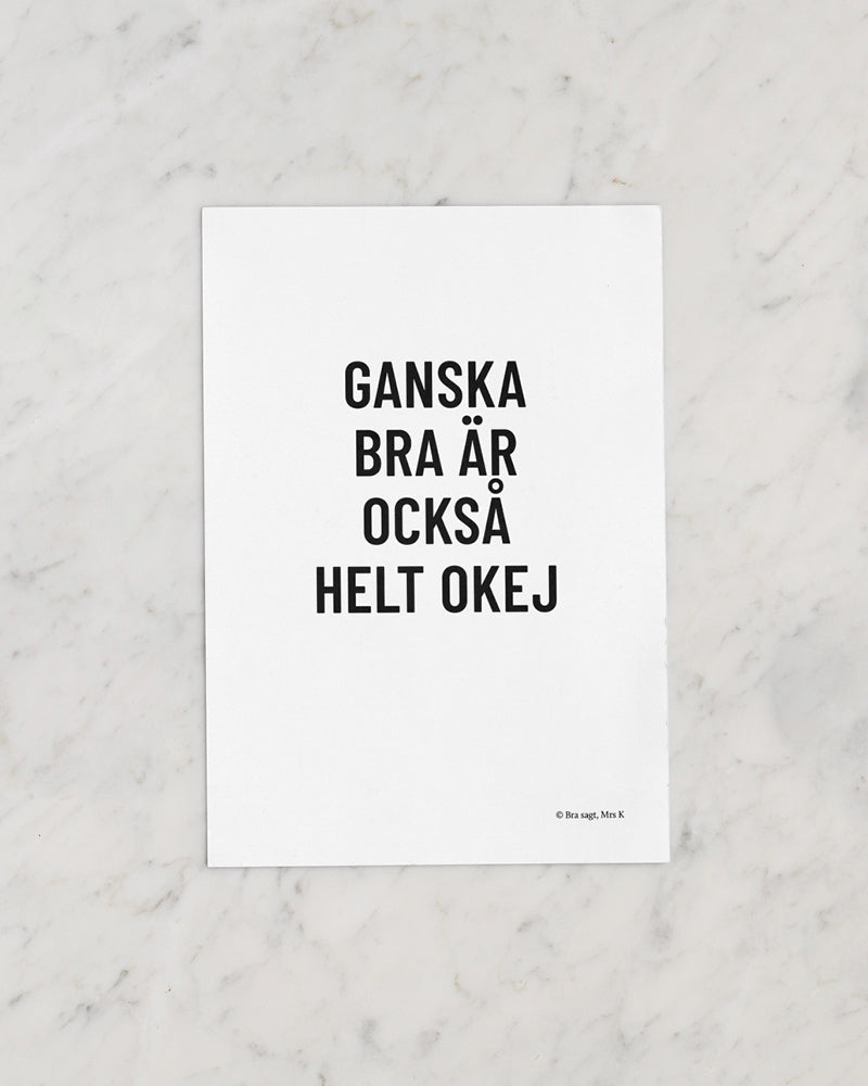 Poster med svenska citatet "Ganska bra är också helt okej" placerat på marmor.