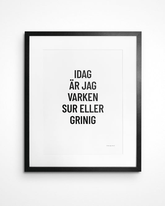Poster med svenska citatet "Idag är jag varken sur eller grinig" i ram på vägg.