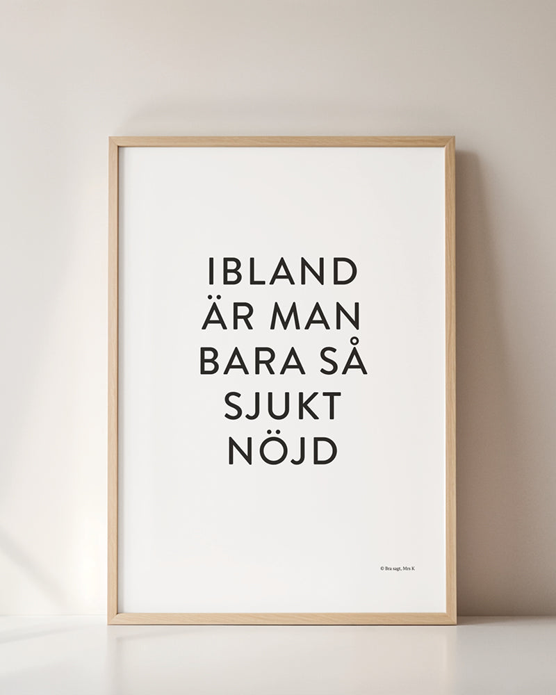 Poster med svenska citatet "Ibland är man bara så sjukt nöjd" i ram mot vägg.