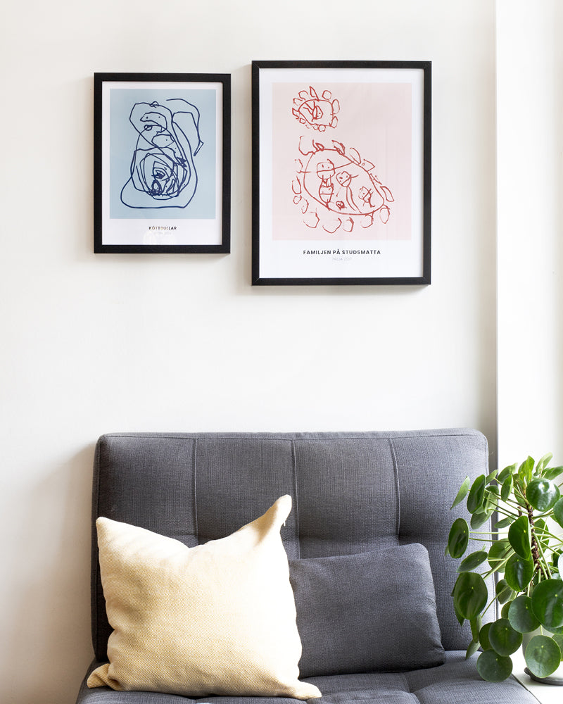 Två olika barnposters i ramar på vägg ovanför en soffa. 