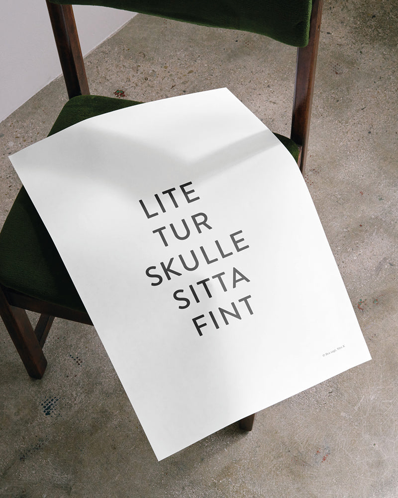 Poster med svenska citatet "Lite tur skulle sitta fint" placerat på en stol. 